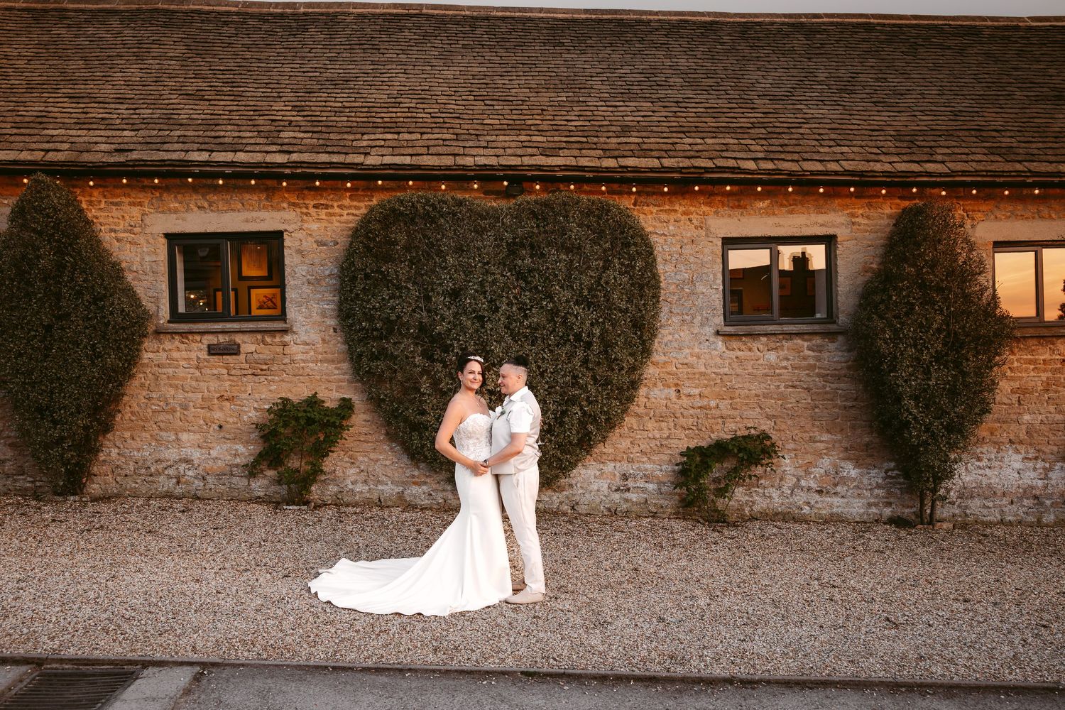 Wedding photos displayed against a rustic brick wall backdrop with windows.