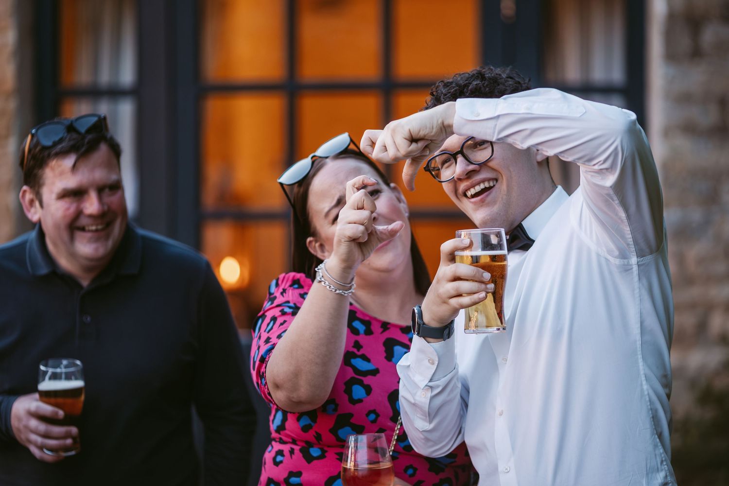 People socializing and laughing together at an evening outdoor event with drinks.