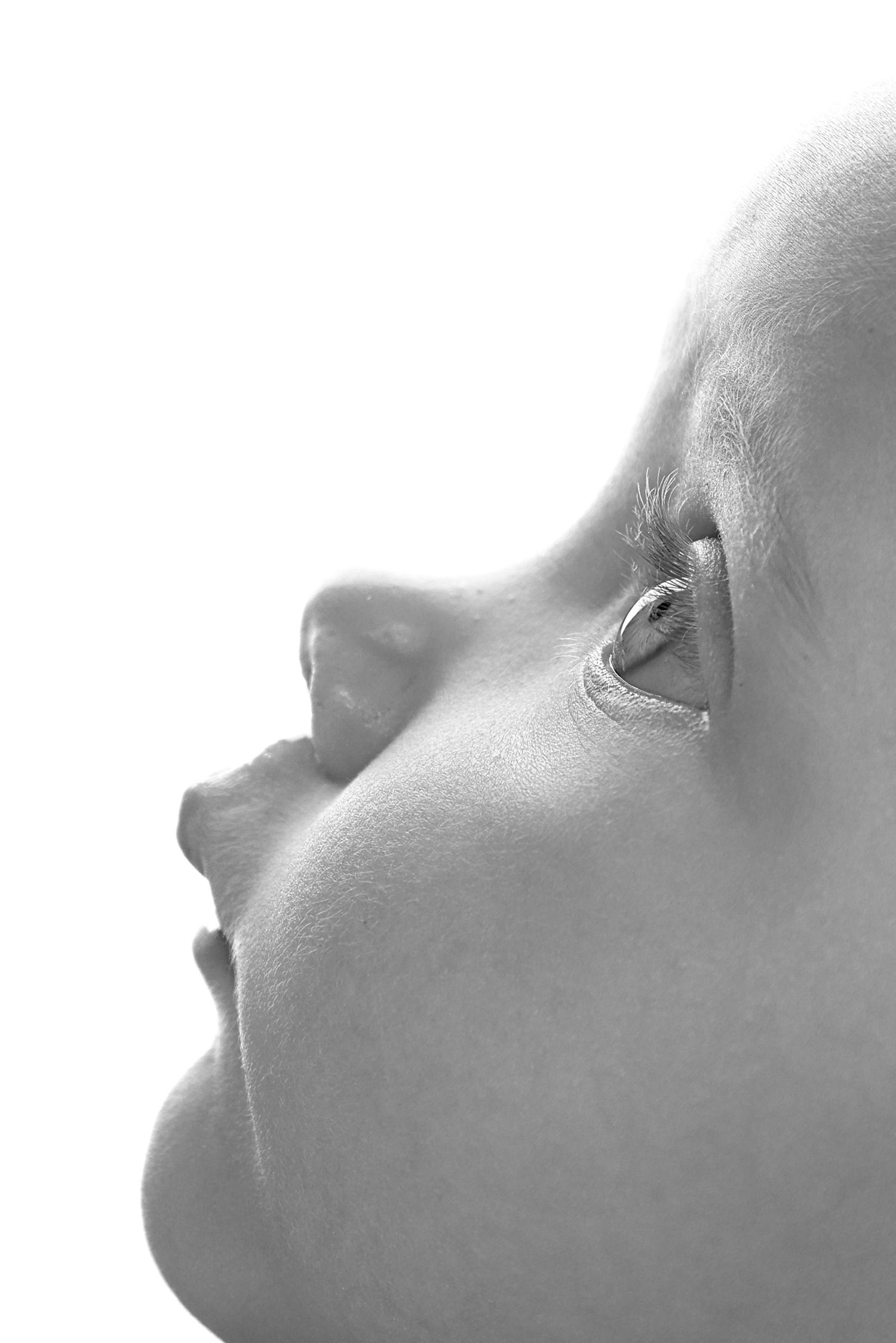 Close-up black and white profile portrait of a baby's face looking upward against white background. R.A.M Photography, Stranraer