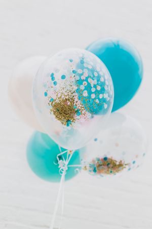 Transparent balloon filled with blue liquid and gold glitter against a white background creates a magical effect.