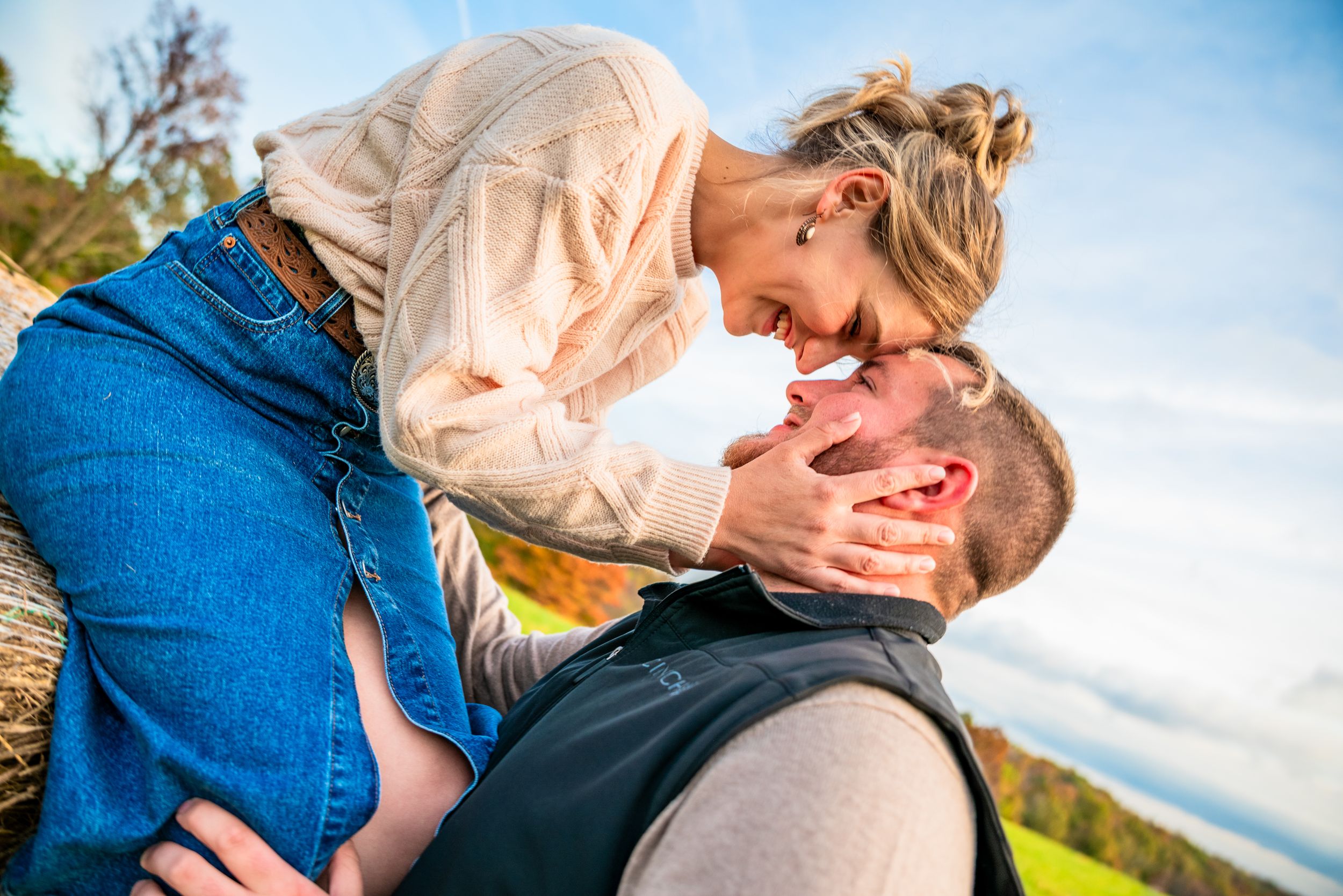 Intimate engagement photos captured against a bright blue sky backdrop.