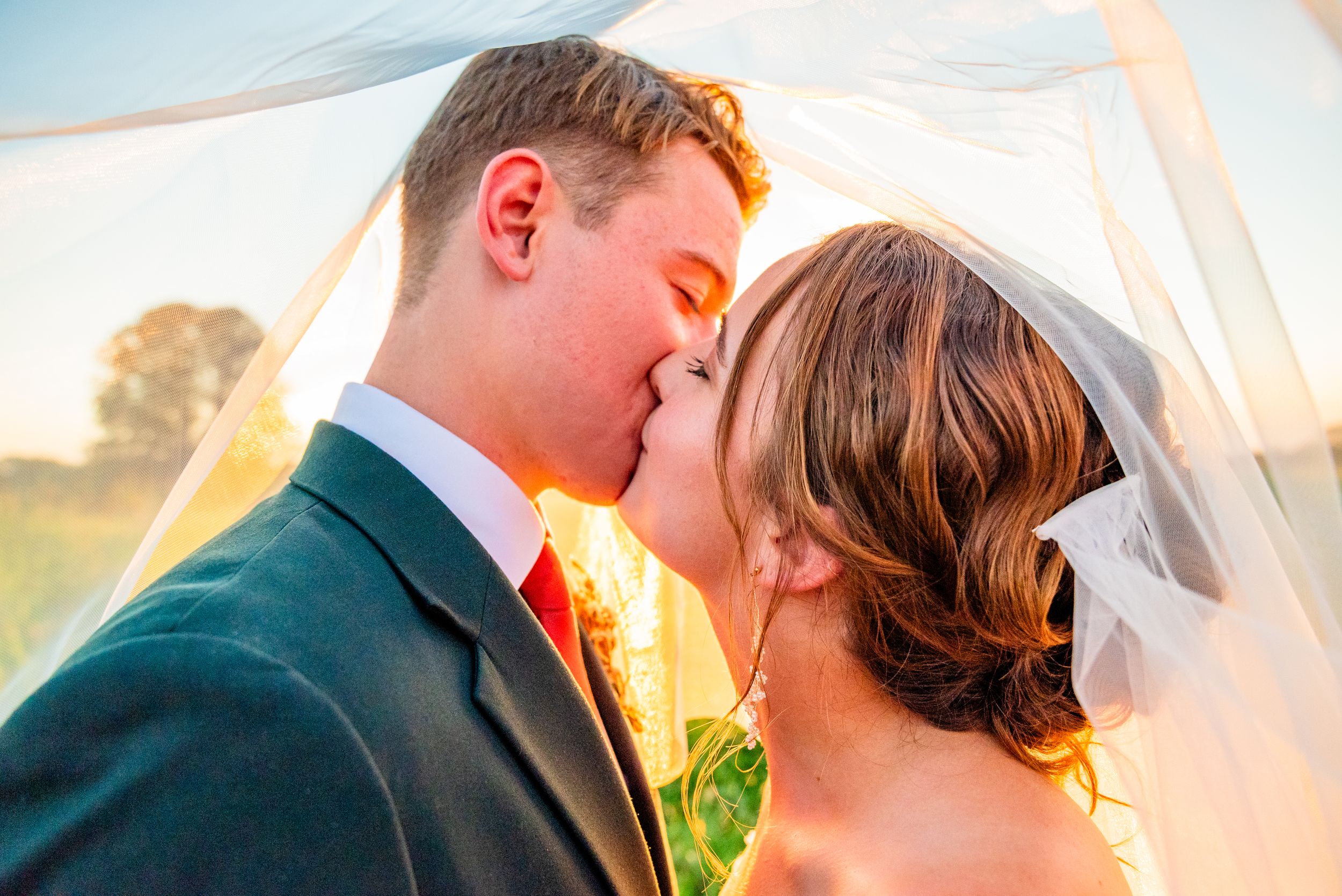 Romantic sunset wedding portraits showing tender moments between newlyweds against golden light.