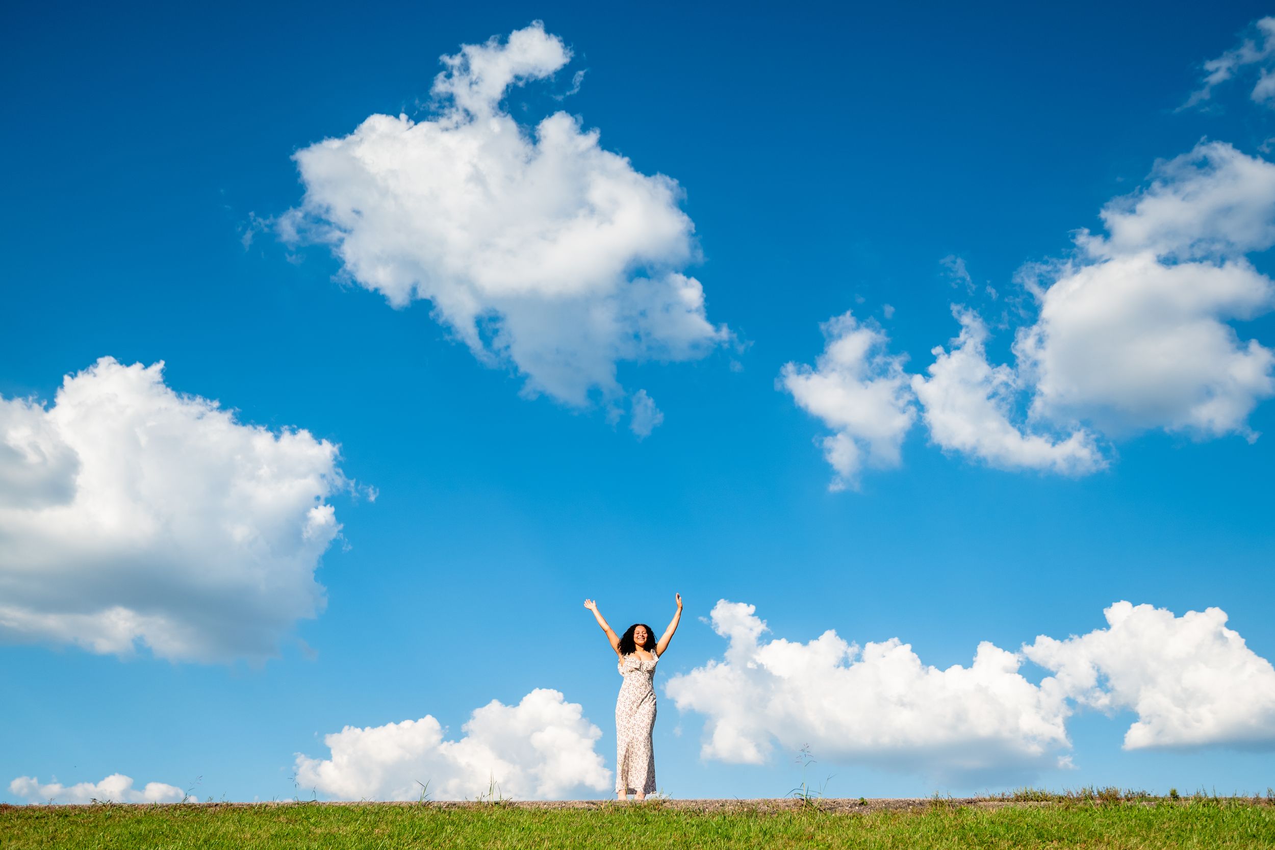 Panoramic view of blue sky with puffy white clouds over green rolling hills.