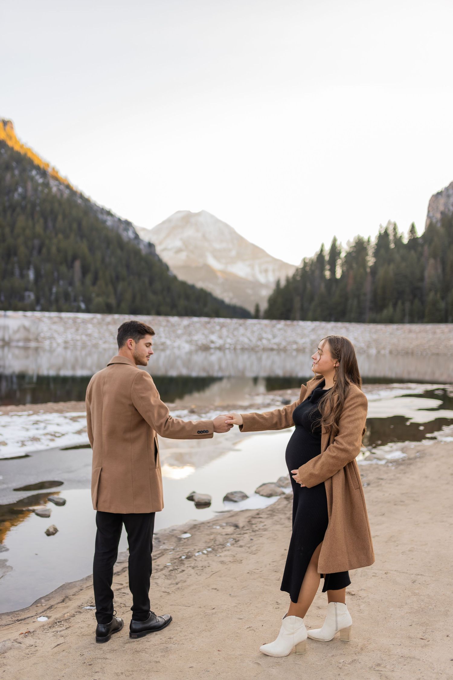 Maternity couple holding hands near a mountain lake in Utah during an intimate outdoor maternity session