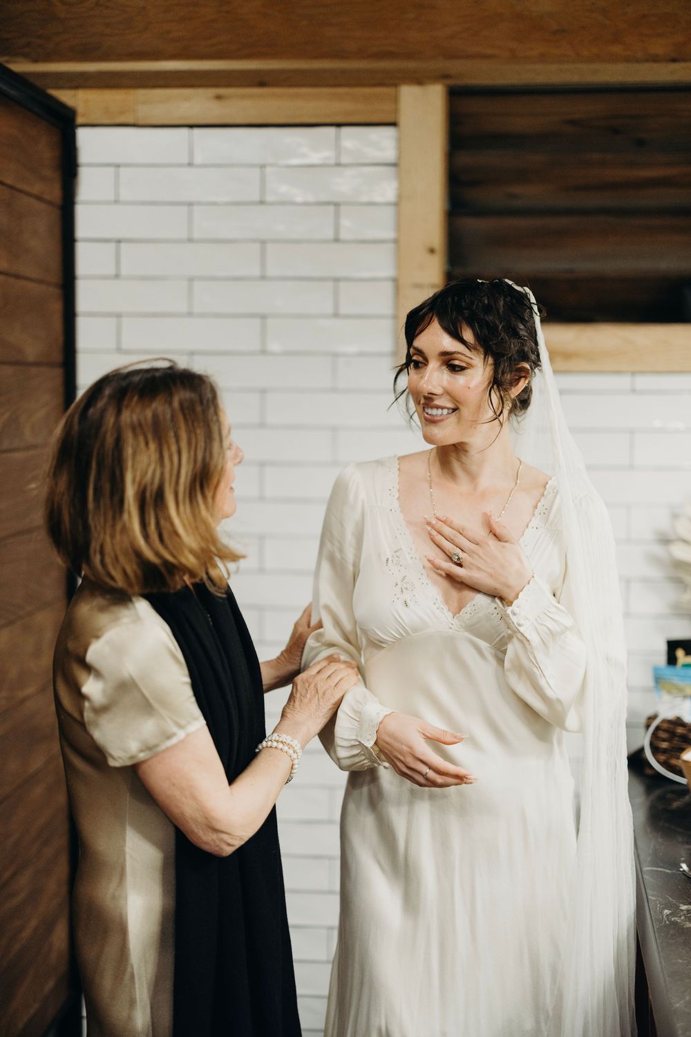 Getting ready moments captured in an intimate indoor setting with white dress.