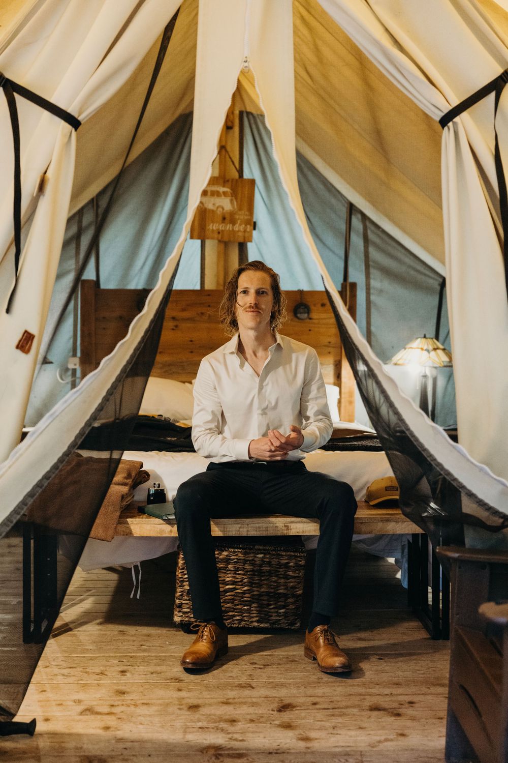 Interior of elegant white tent with rustic wooden flooring and draped fabric walls.