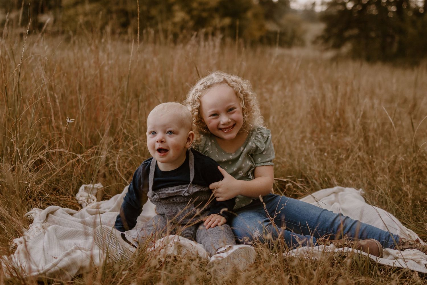 Family members lying together in a golden autumn field during a warm sunset photography session.