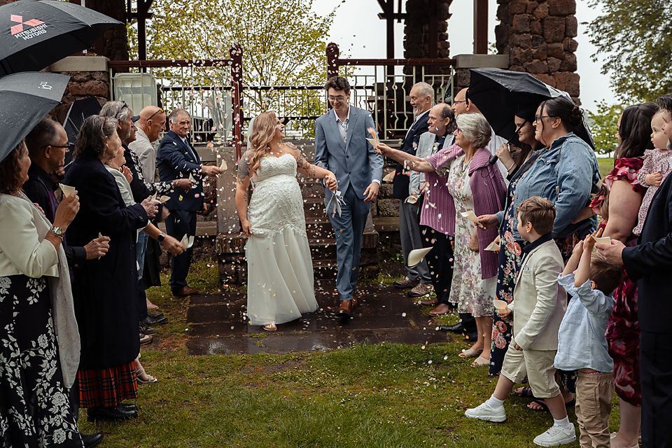 Wedding guests line up outside to create a bubble-filled sendoff tunnel for the newlyweds.