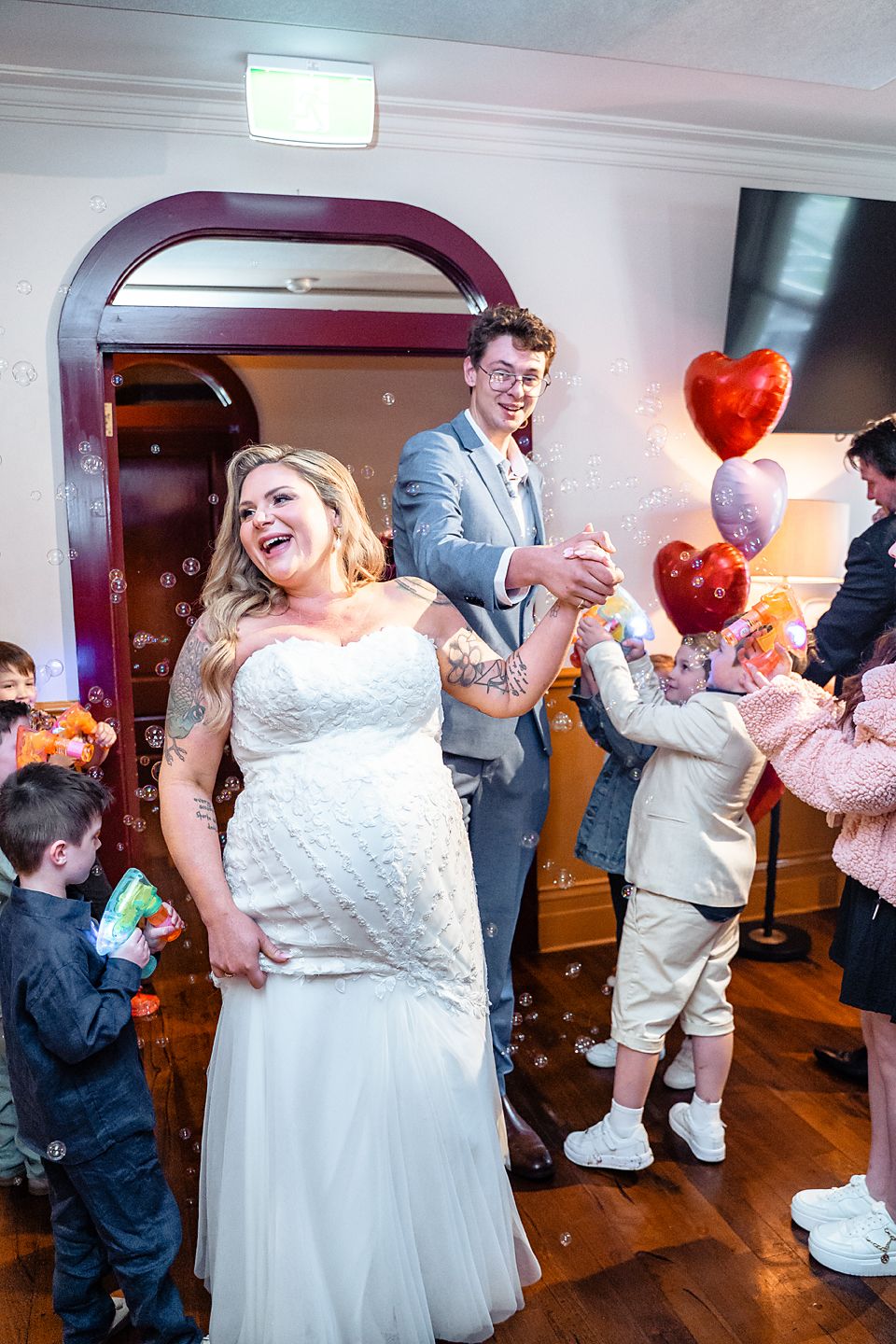 A joyful celebration on the dance floor with heart-shaped balloons and confetti at an indoor wedding reception.