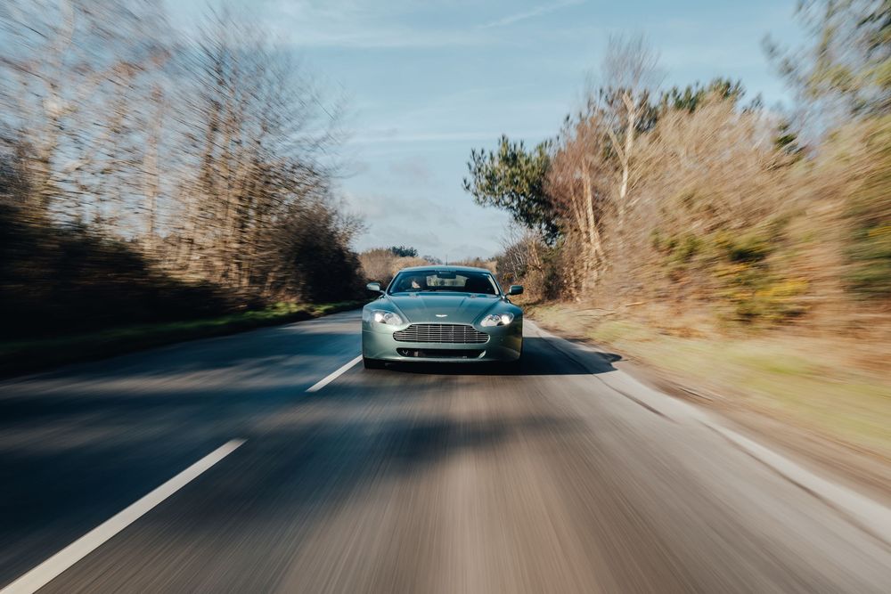 Dynamic driving shot of sports cars on a winding country road during daytime.