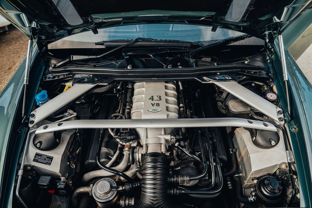 Under-hood view of a pristine Aston Martin engine bay with exposed mechanical components.