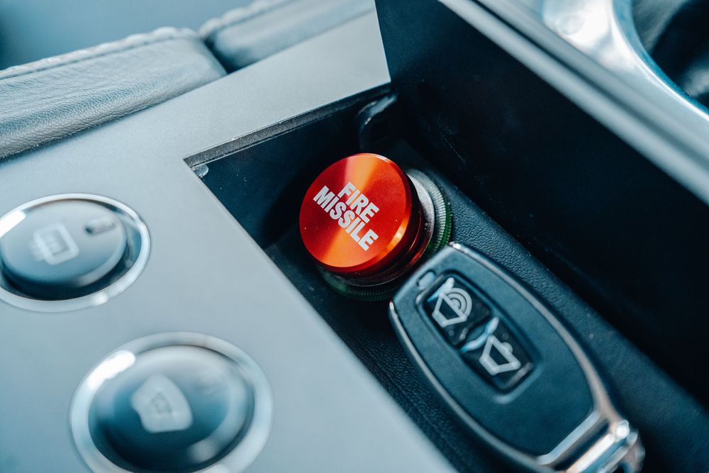 Close up view of car interior controls showing parking brake and gear shift buttons in modern vehicle.