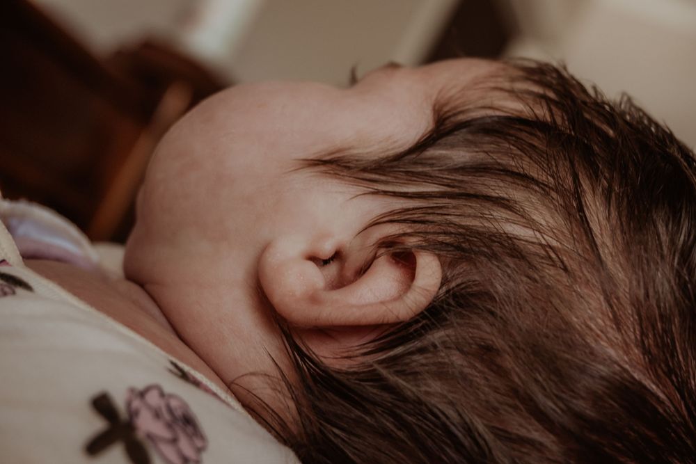 Close-up detail of a baby's ear and dark hair during a central coast newborn session.