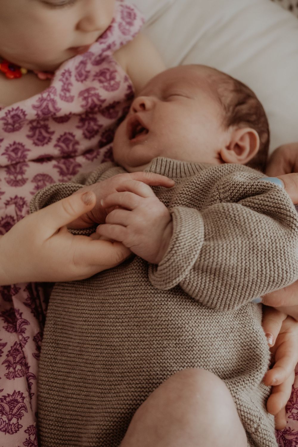 Older sister and newborn baby sharing sweet moment during a central coast newborn photoshoot.