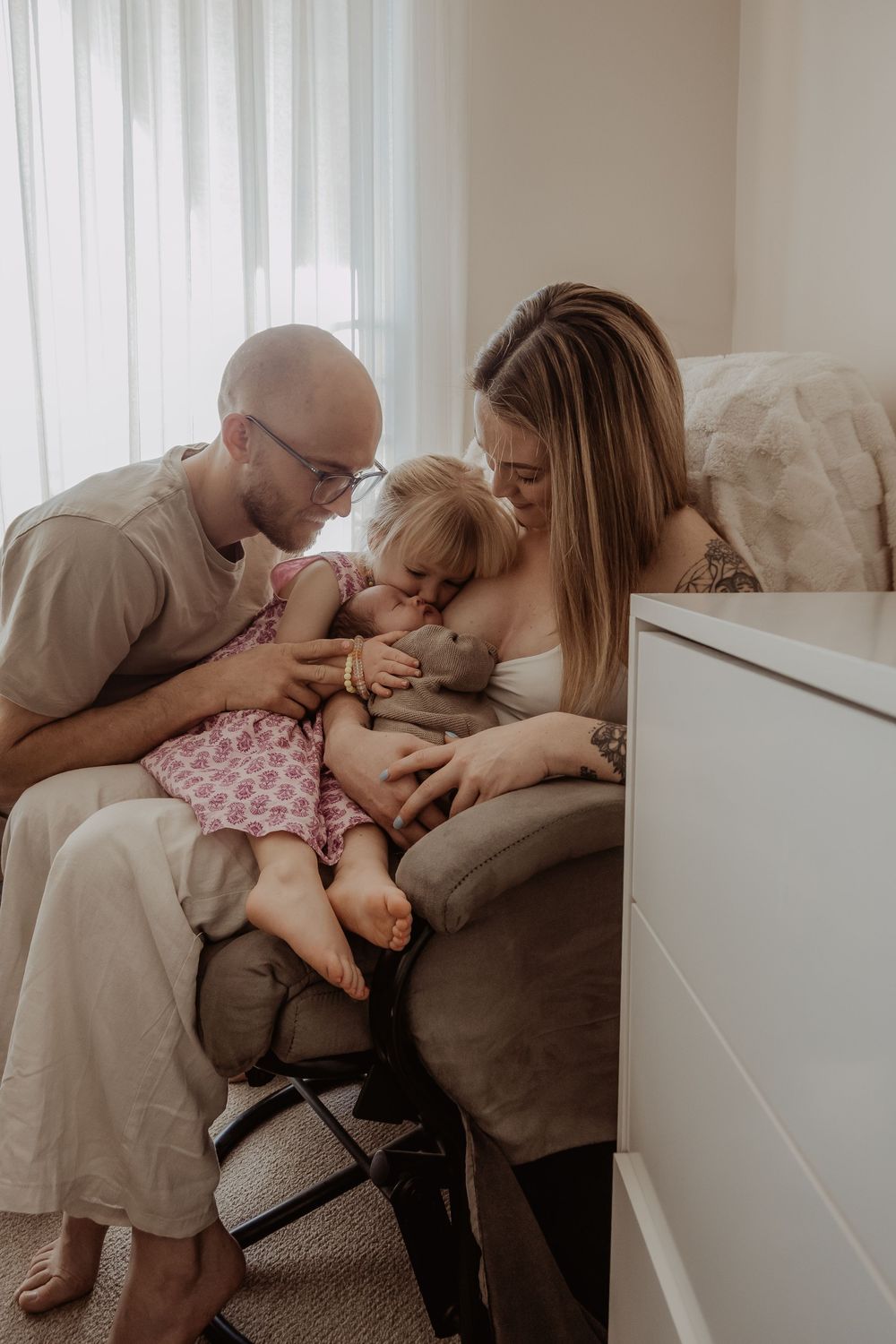 Family cuddle session on rocker showing playful interaction and connection during a central coast newborn photoshoot.