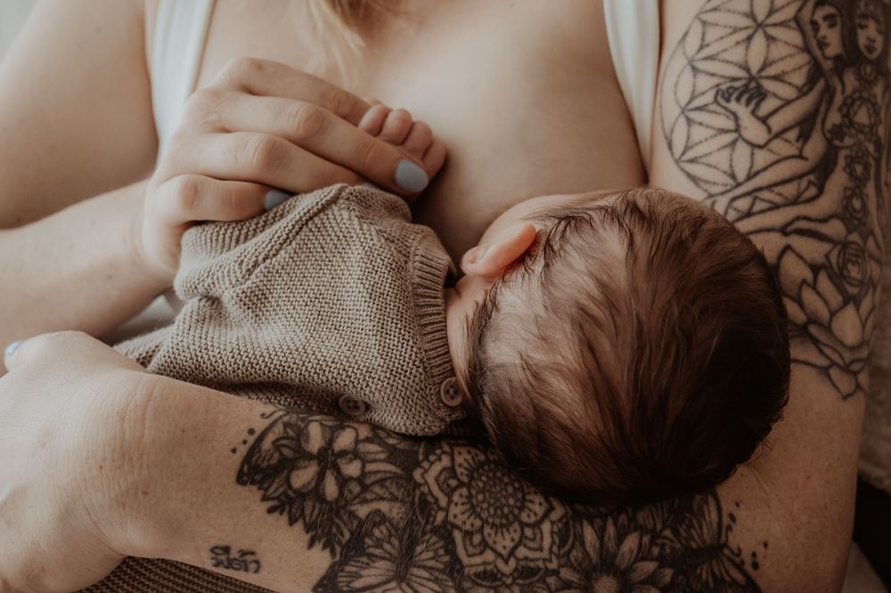 Close-up of a newborn baby nursing wearing a soft knit sweater during a central coast newborn photoshoot.