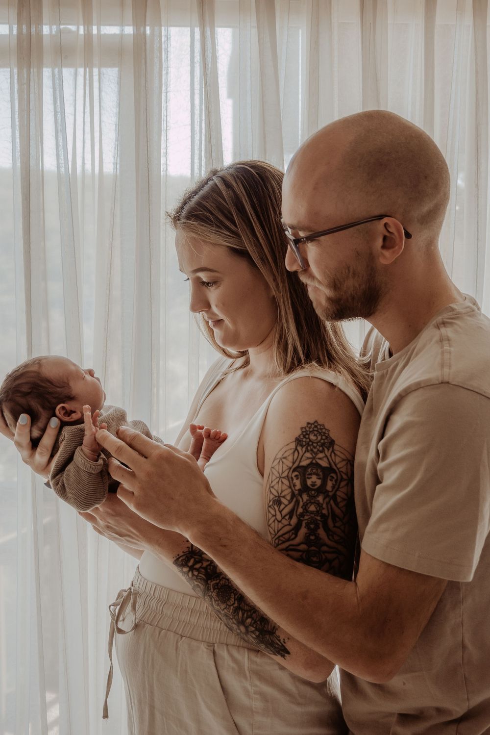 Intimate family moment with newborn baby being held and admired in a softly lit room during a central coast newborn photoshoot.