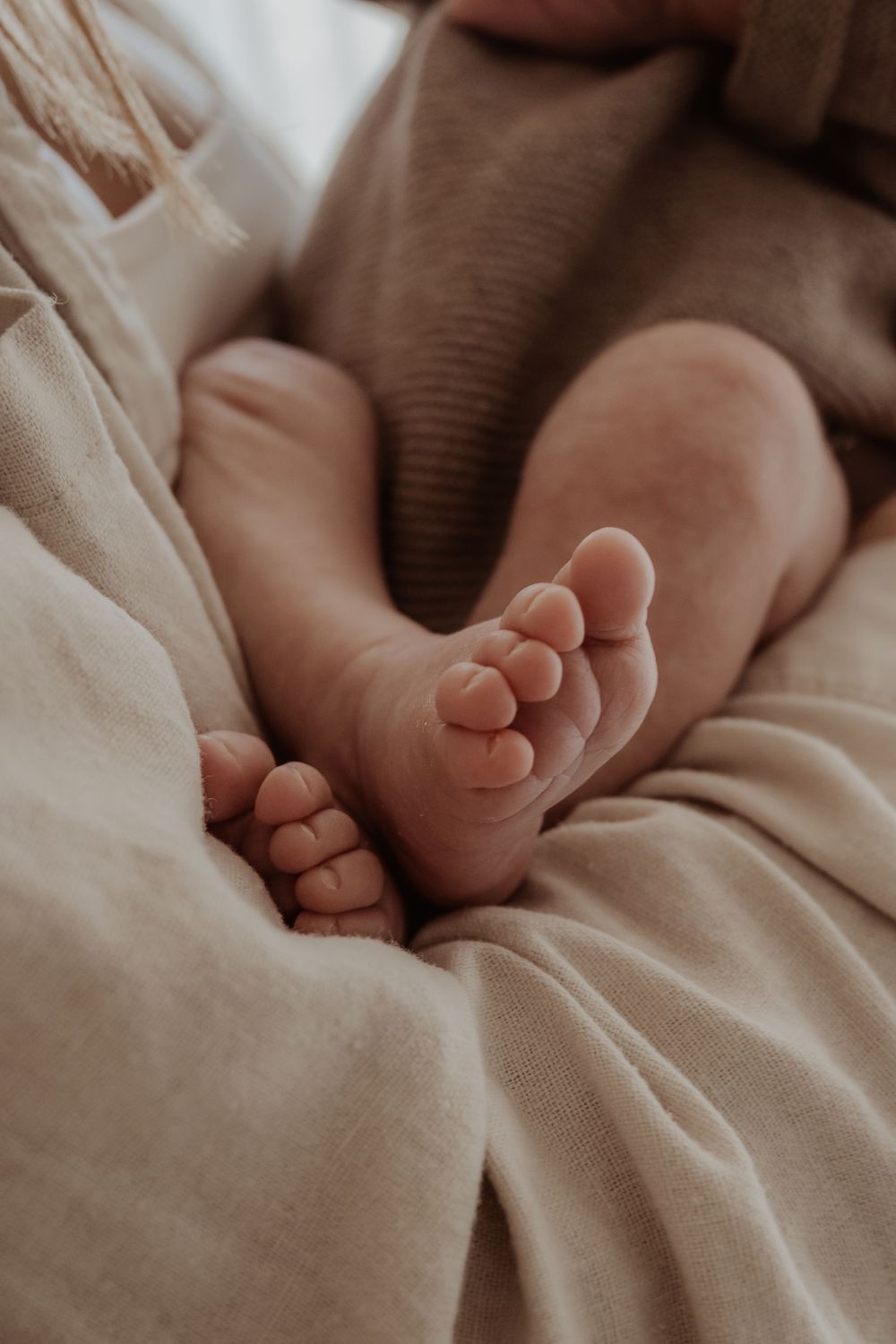 Tiny baby feet resting on soft beige fabric in natural light during a central coast newborn photoshoot.
