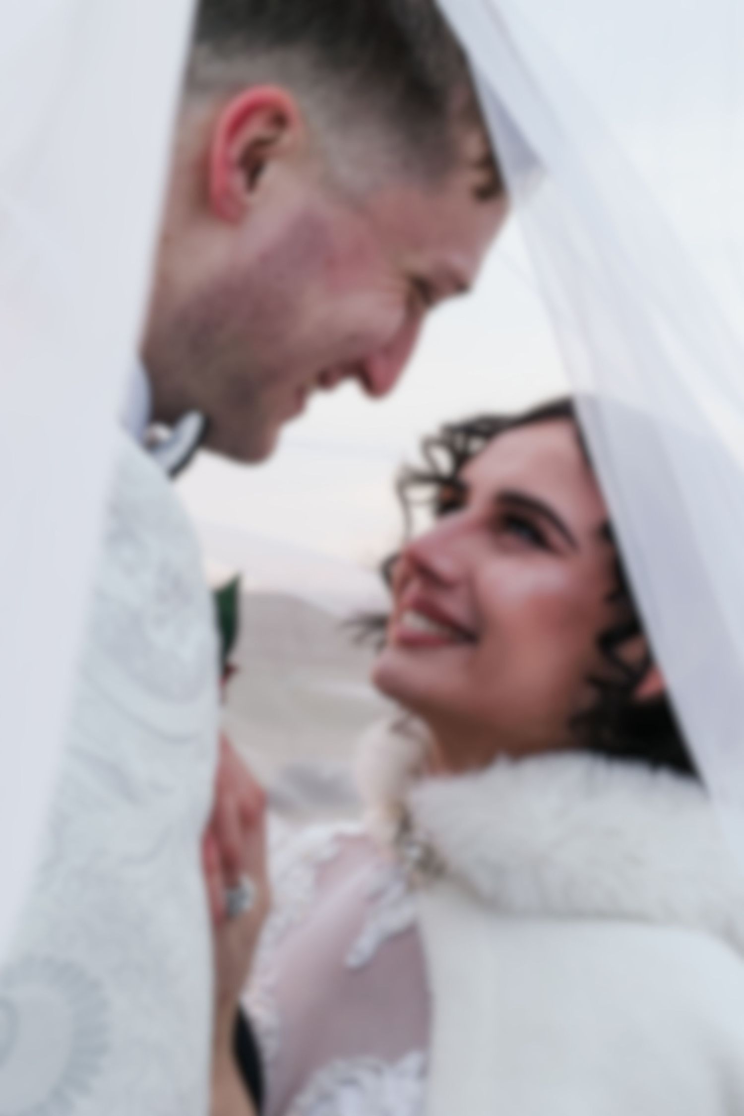 A romantic moment captured between a couple under flowing white fabric.