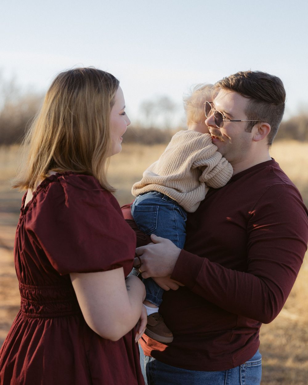 A romantic couple shares tender moments in a field during a sunset photoshoot sequence.