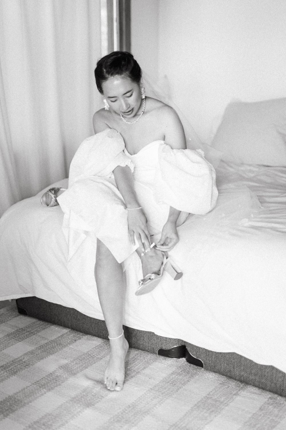 Black and white photo of person in white attire on patterned carpet.