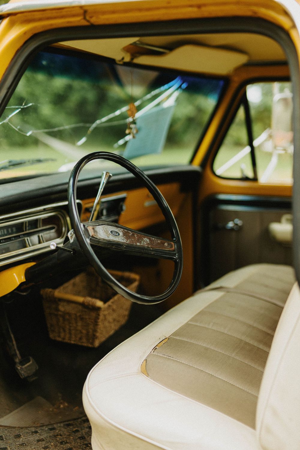 Interior view of a vintage yellow car showing cream leather seats and classic steering wheel.