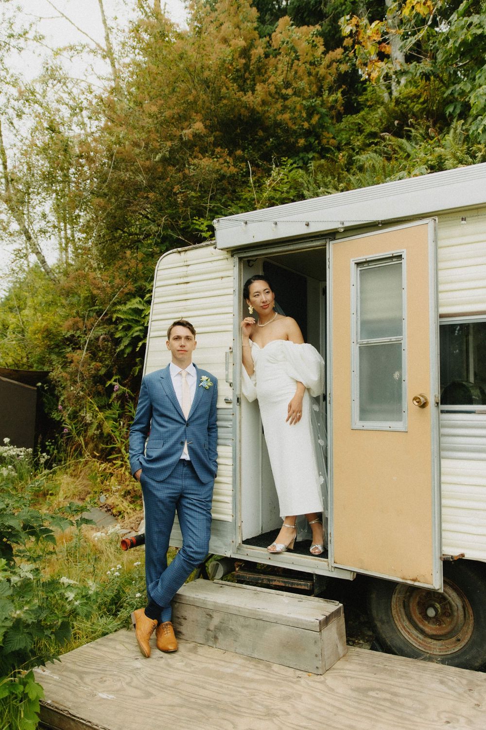 A wedding photo series featuring a couple posing playfully outside a vintage trailer.