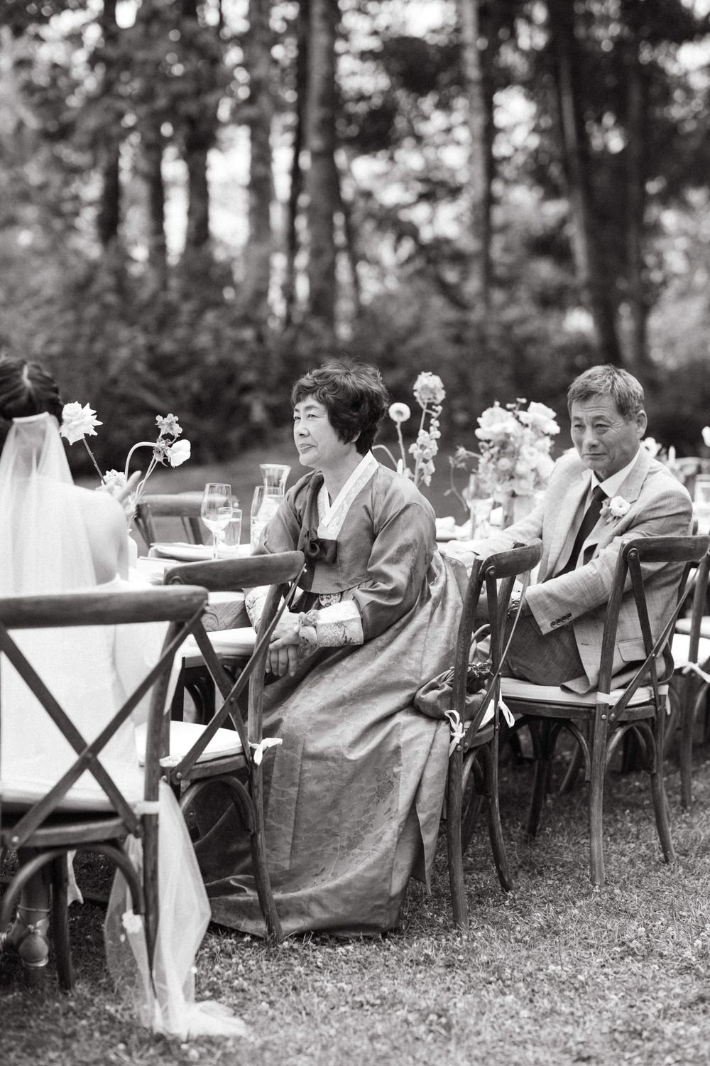 Wedding party lounging in chairs outdoors with floral decorations.