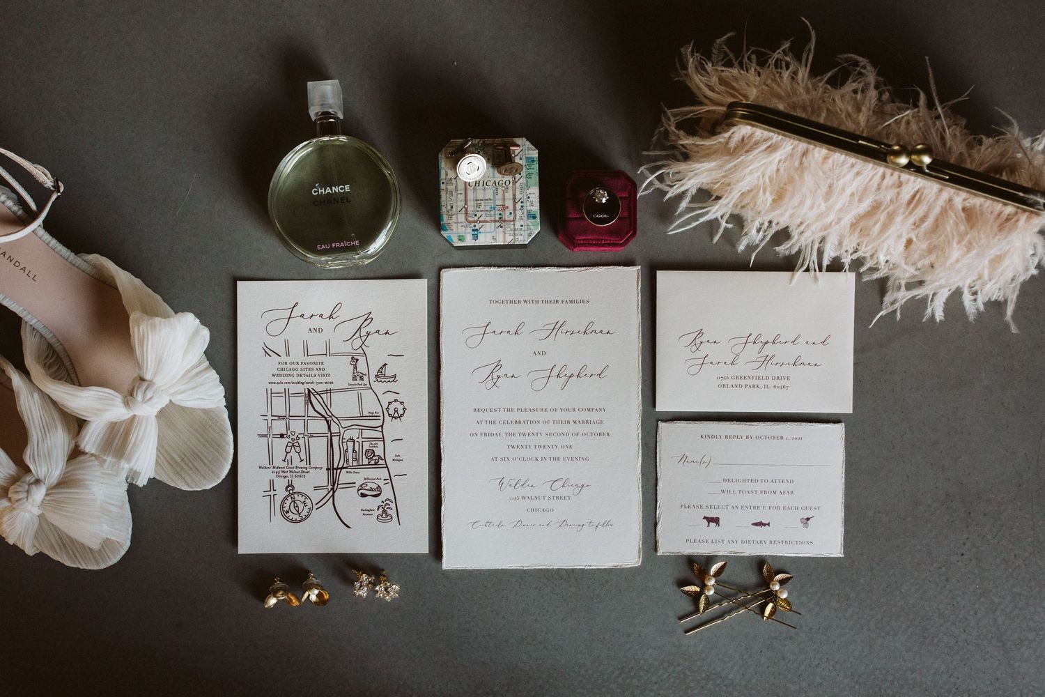 Wedding invitation suite with elegant calligraphy and floral designs laid out on a dark surface.