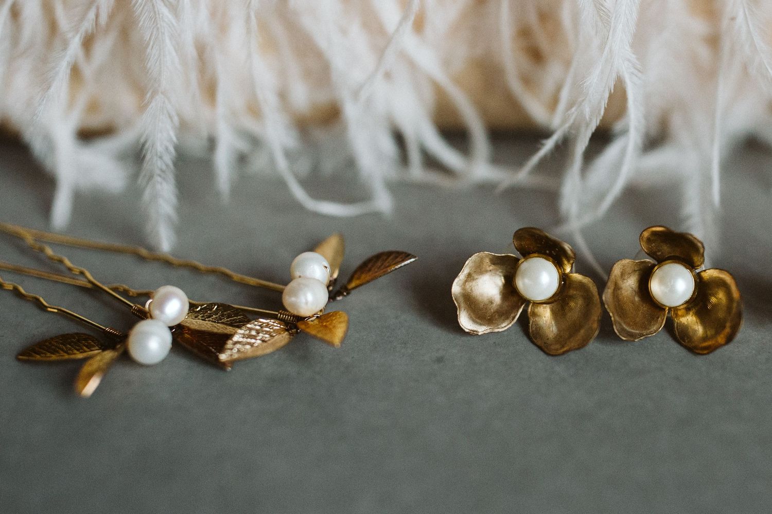 Decorative golden twigs and white feathers arranged artistically on a light surface.