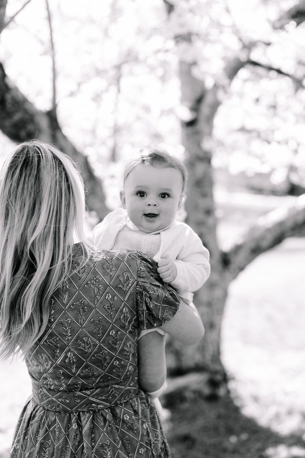 Baby boy during a flowering mini session in Marietta GA  looking over his mom's shoulder