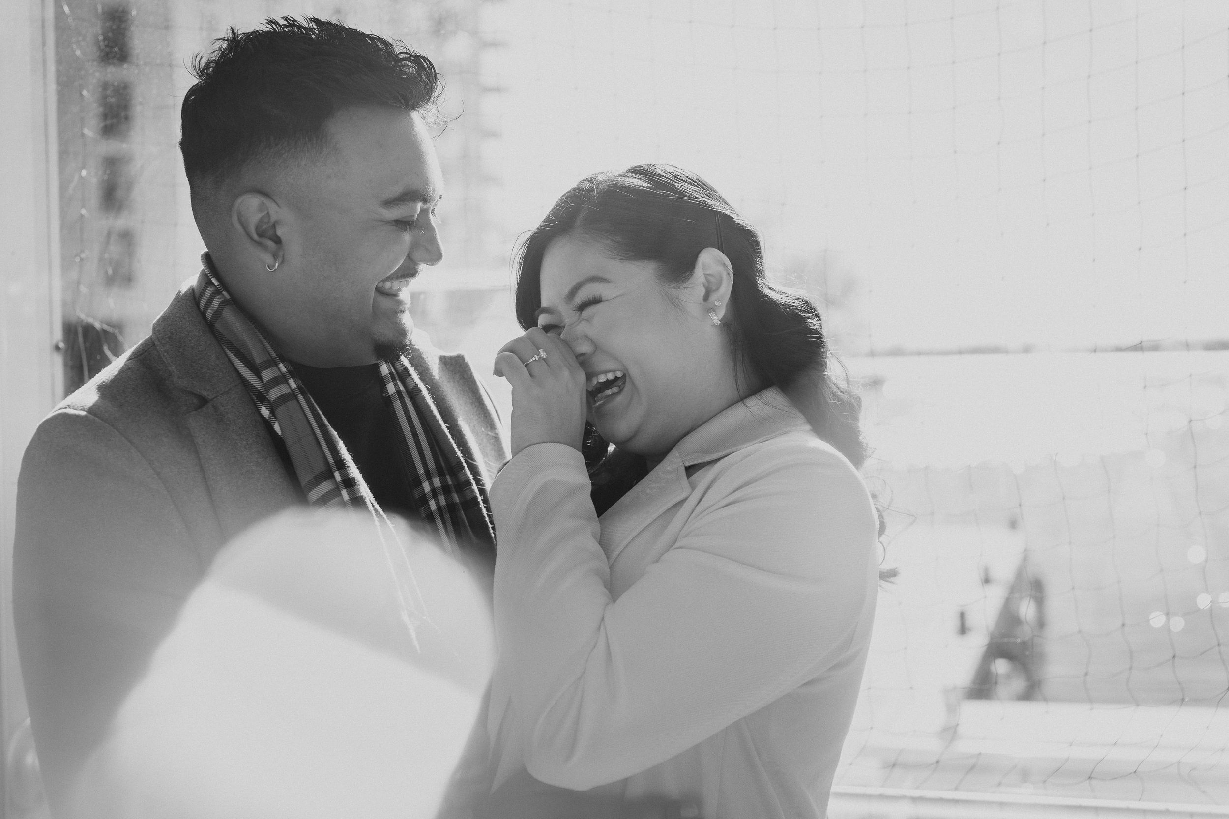 A romantic black and white portrait of a couple sharing a joyful intimate moment together.