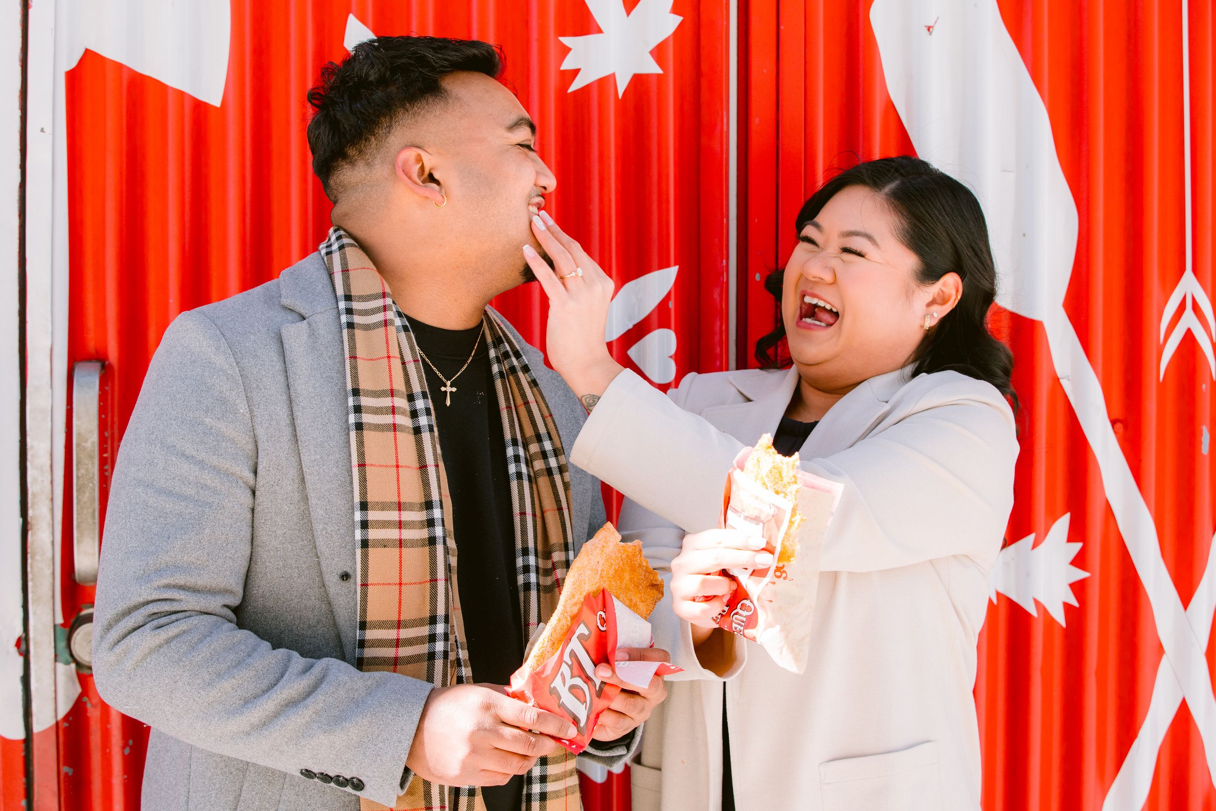 A couple sharing laughter and snacks against a vibrant red backdrop with decorative white stars.