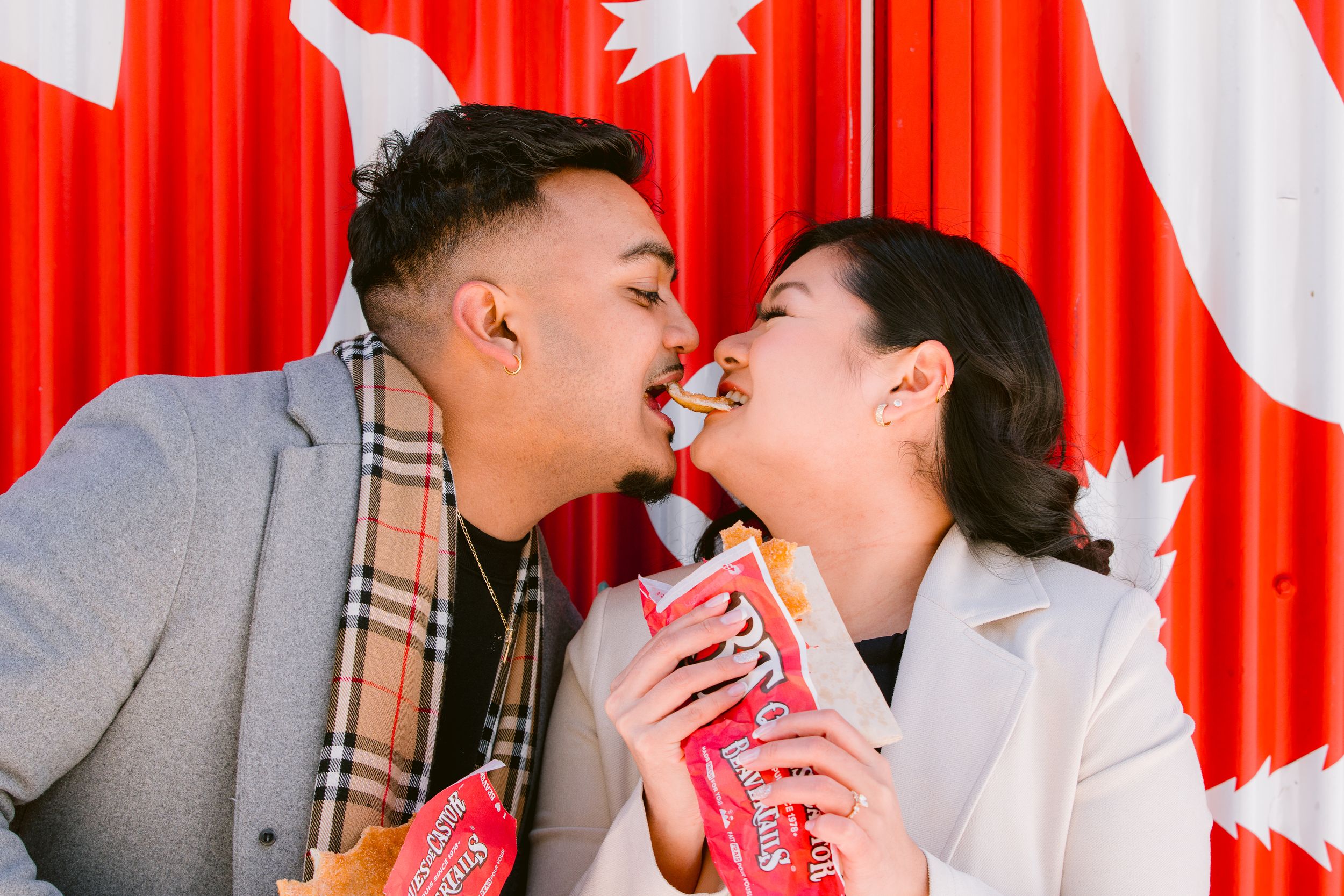 Couple sharing a romantic moment with drinks against a vibrant red and white backdrop.