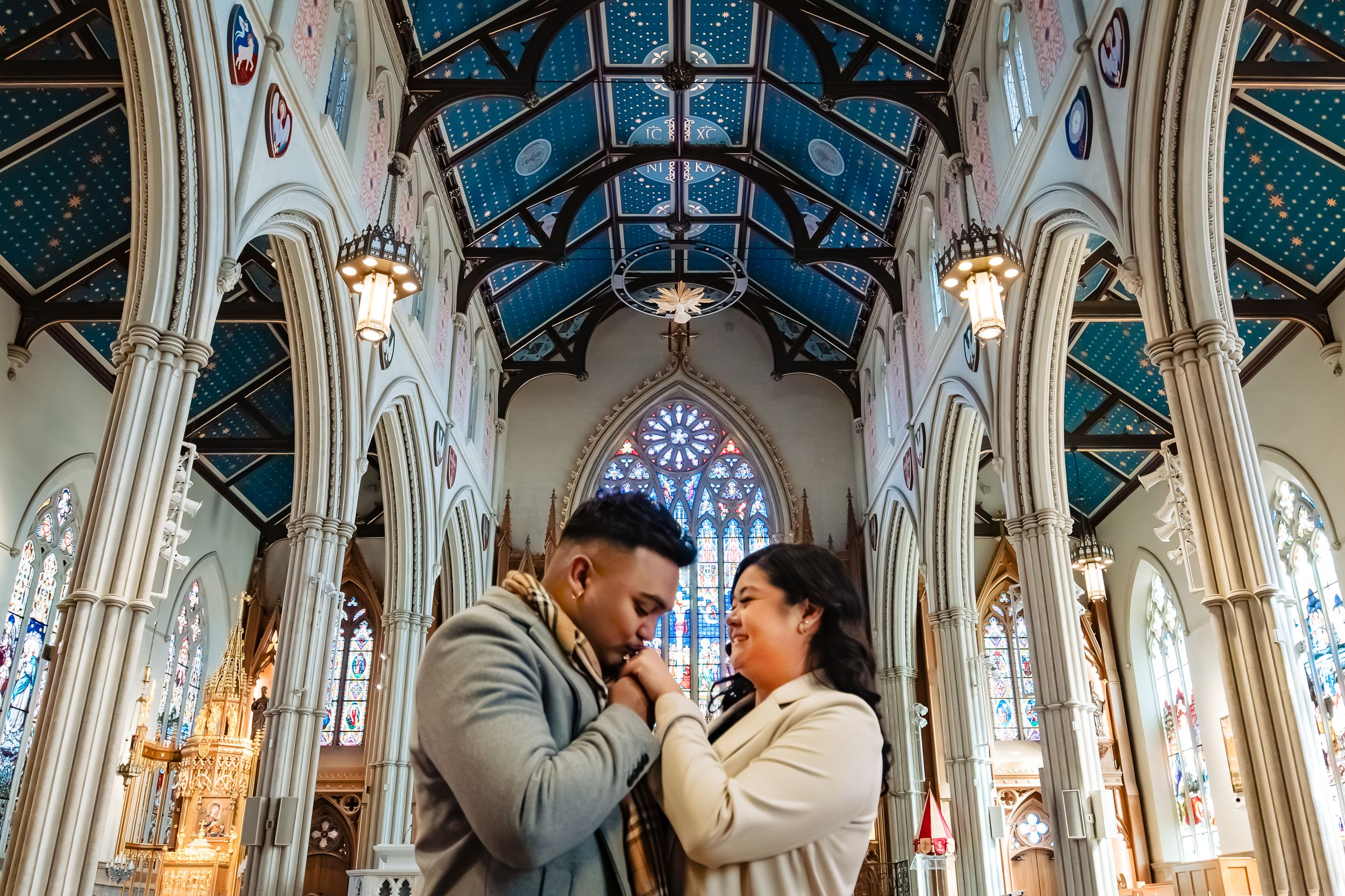 Intimate couple portrait inside a gothic cathedral with stunning stained glass and blue vaulted ceiling.