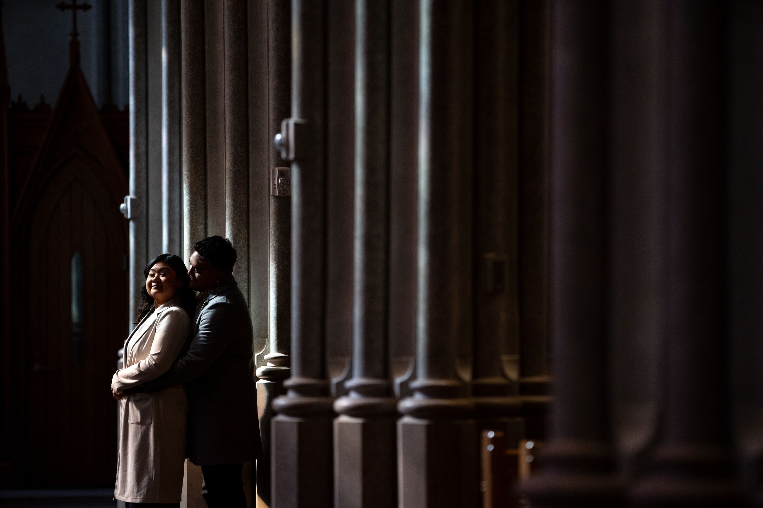 Dramatic light falls between ornate church columns creating a moody architectural scene.