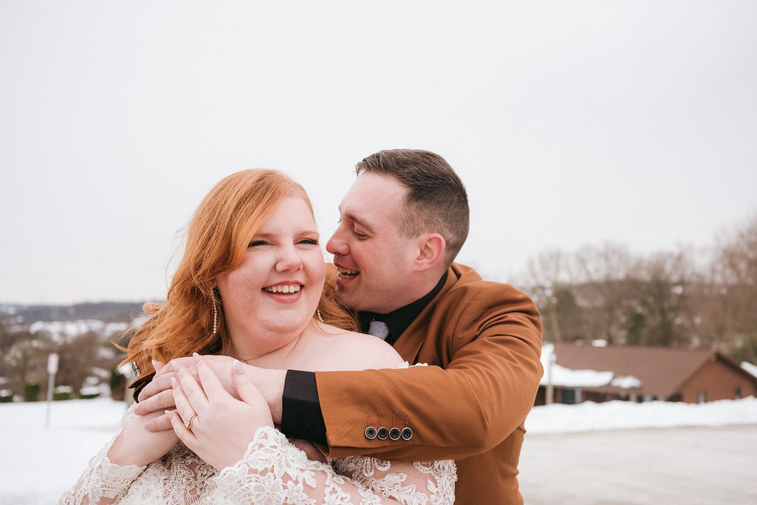 A romantic couple shares an intimate moment outdoors, with one partner wearing a blue suit and white bowtie.