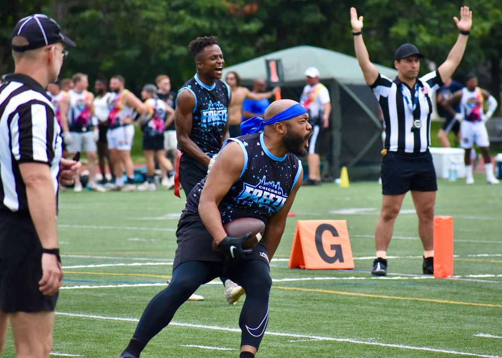 A CMSA flag football player celebrates a touchdown at Pride Bowl in Chicago at Montrose Beach Track and Field near Cricket Hill