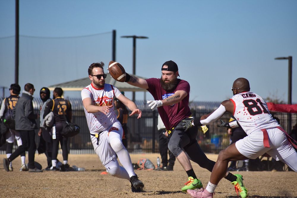 A football player reaches forward with the ball while two opponents on the Chicago Blaze representing CMSA attempt to pull his flags