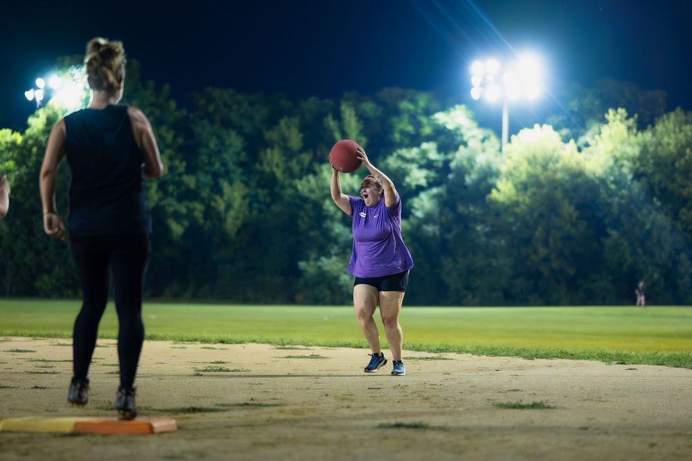 An athlete celebrates catching the kickball for an out under stadium lights at a park in Chicago