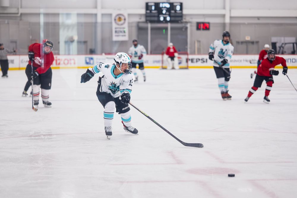 A hockey athlete chases the puck to maintain control before a shot on the goal