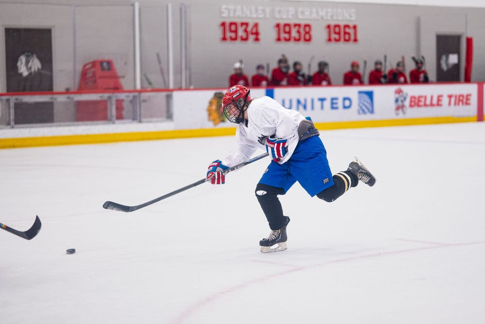 A hockey athlete chases the puck to maintain control before a shot on the goal