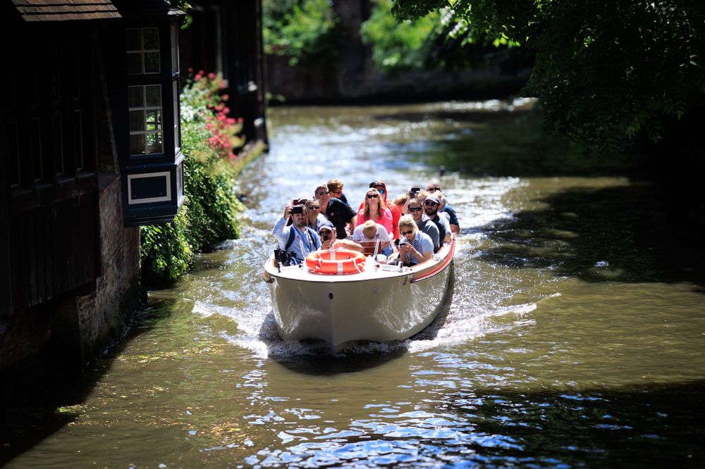 Tourist boats navigate through narrow canals between historic buildings in Bruges.