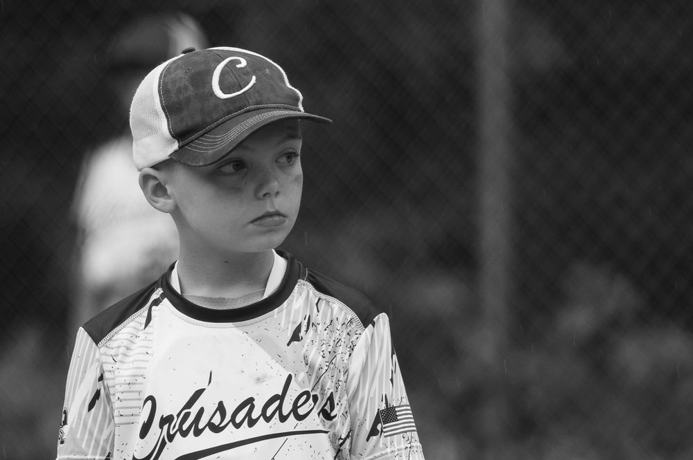 Baseball player in Crusaders uniform stands ready on field during youth baseball game.