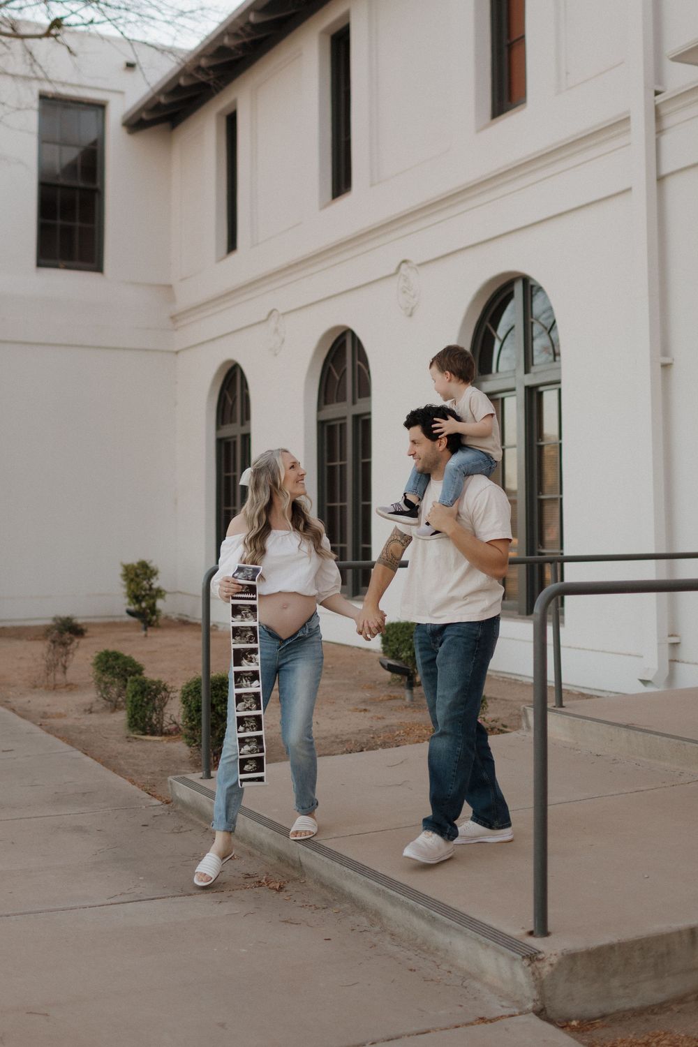 Lifestyle photo of couple walking along white Mediterranean-style building exterior.