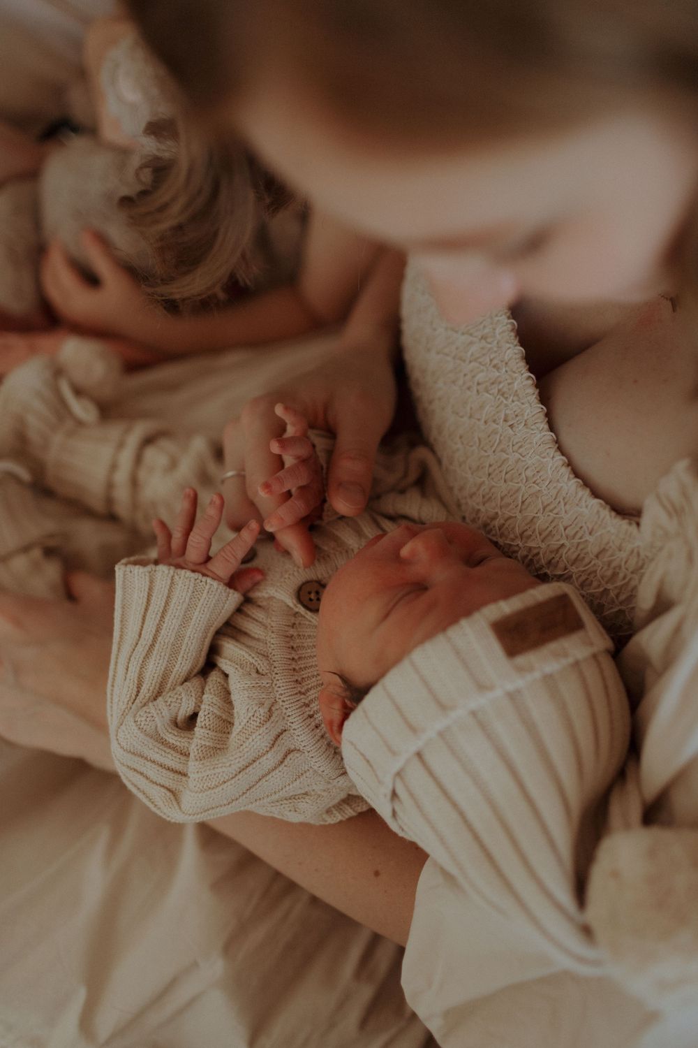 Close-up of newborn baby wearing knitted clothing while being held.