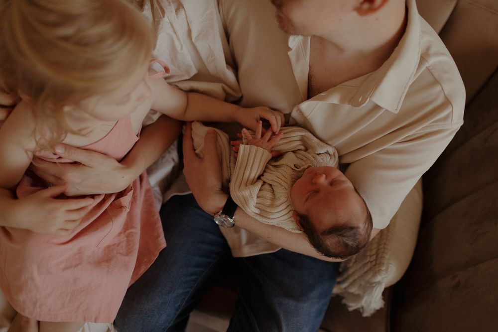 Tender family moment as siblings bond on comfortable couch.