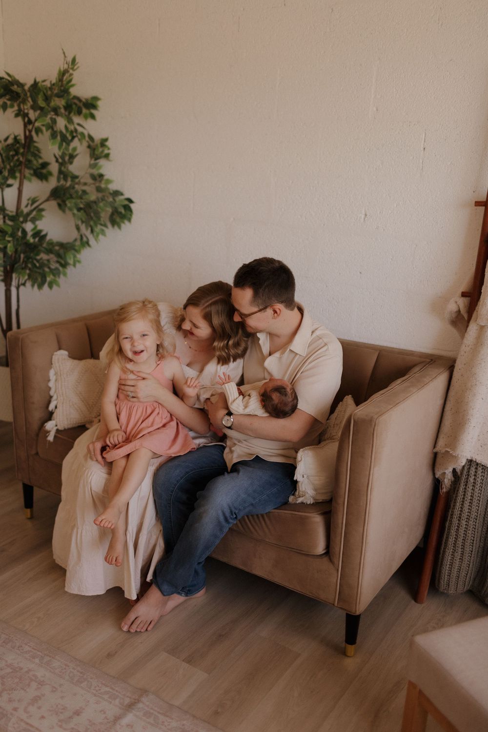 Tender family moment captured in warm tones on a brown couch with minimalist decor.