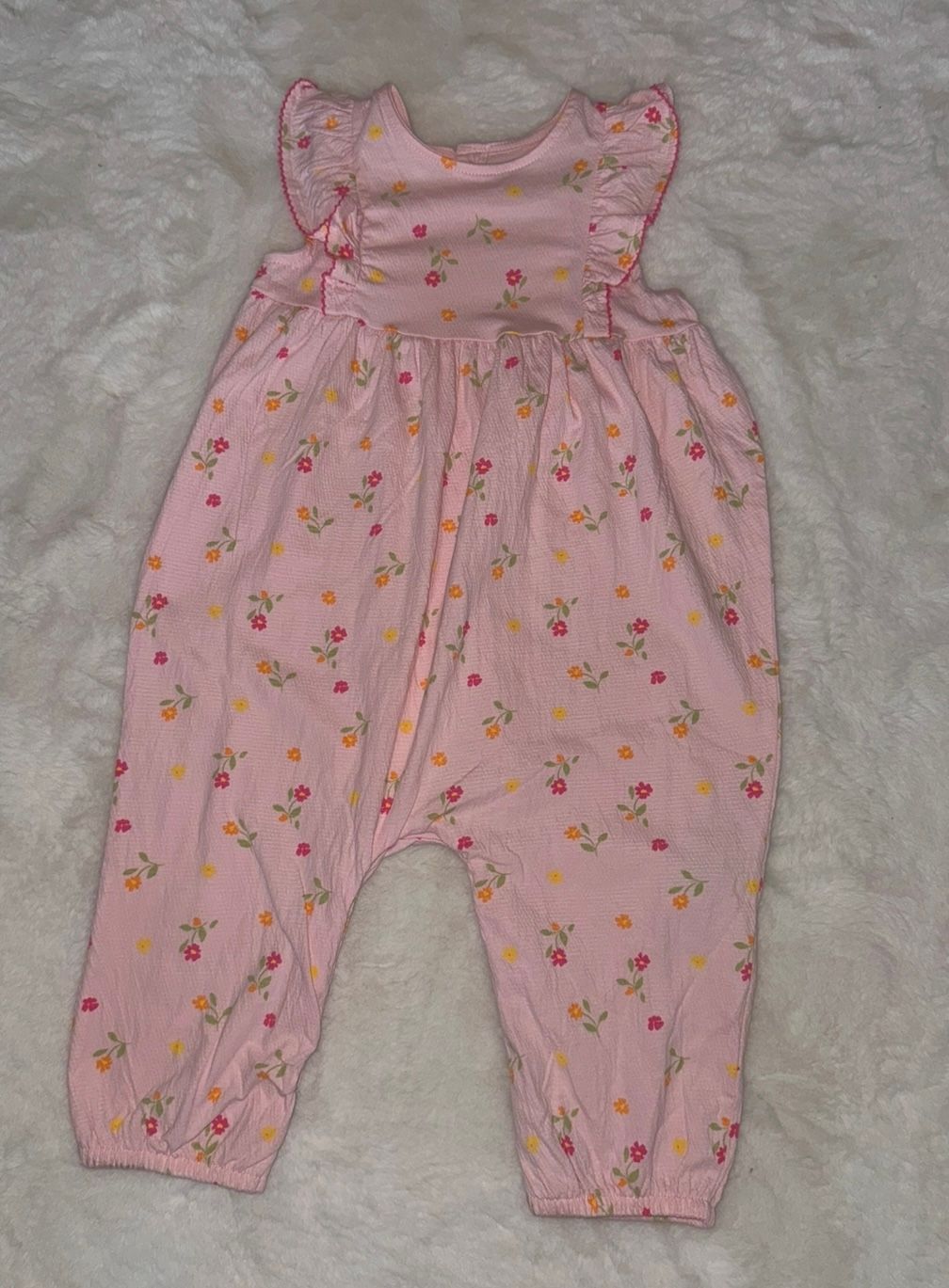 Pink floral print baby romper with ruffled sleeves.