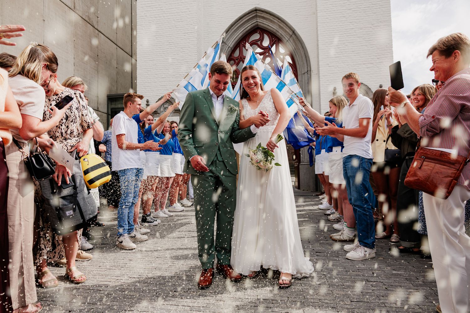 Pas getrouwd koppel komt uit de kerk wanneer er met confetti of rijst gegooid wordt.